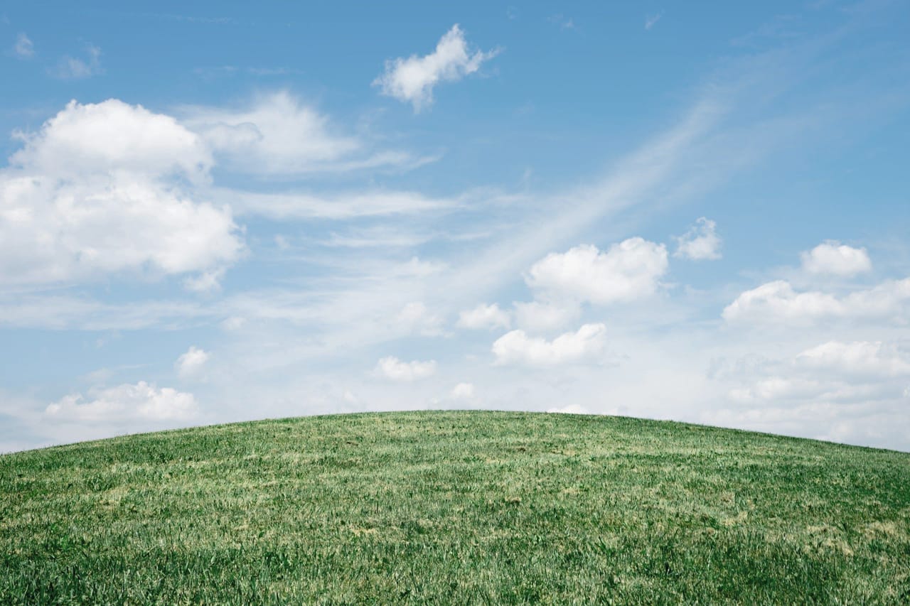 A rolling green hill under a blue summer sky
